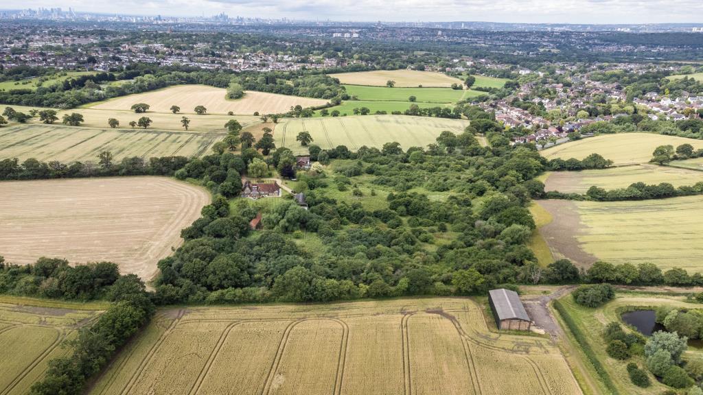 Lot: 105 - OVER NINE ACRES OF FREEHOLD GREENBELT LAND - Drone shot of the land with the City of London in the distance